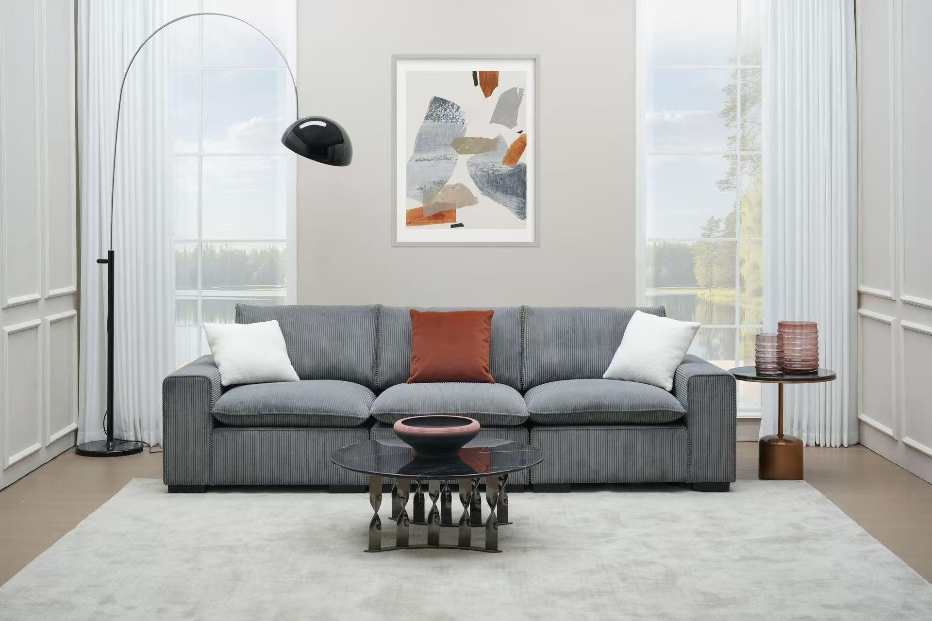 Modern living room with grey corduroy sofa, glass coffee table and contemporary decor