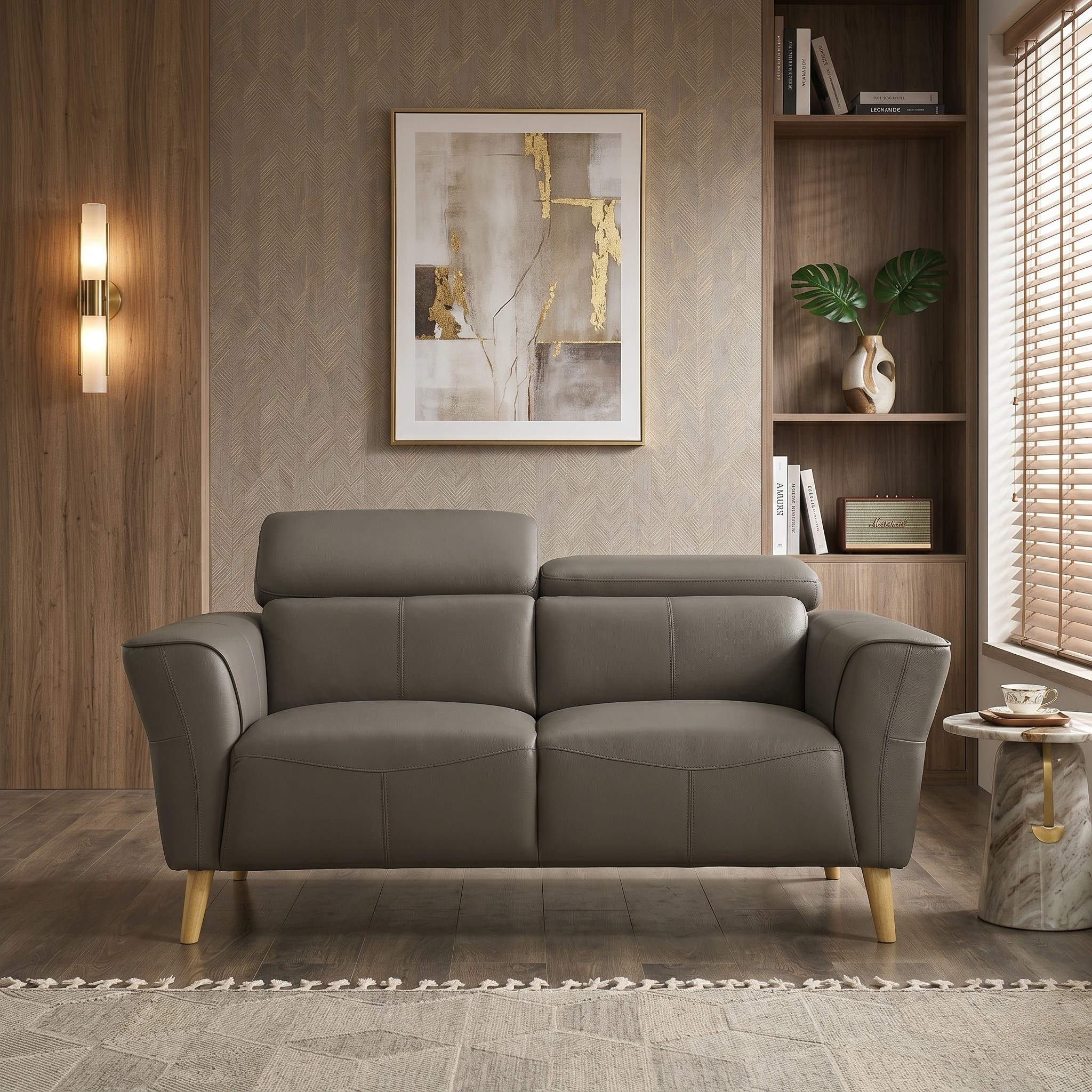 Penelope 2 Seater Leather Lounge sofa in muted gray with wooden legs, placed in a modern living room featuring warm wooden accents, a framed abstract painting, and a marble side table.