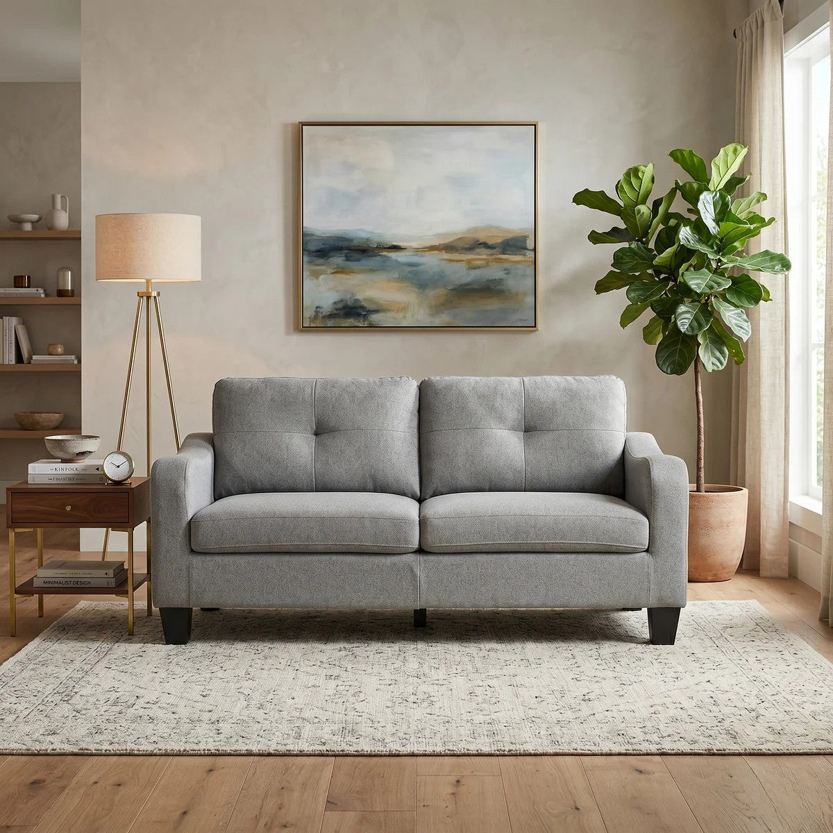 Gray sofa in a living room with a painting, lamp, and plant.