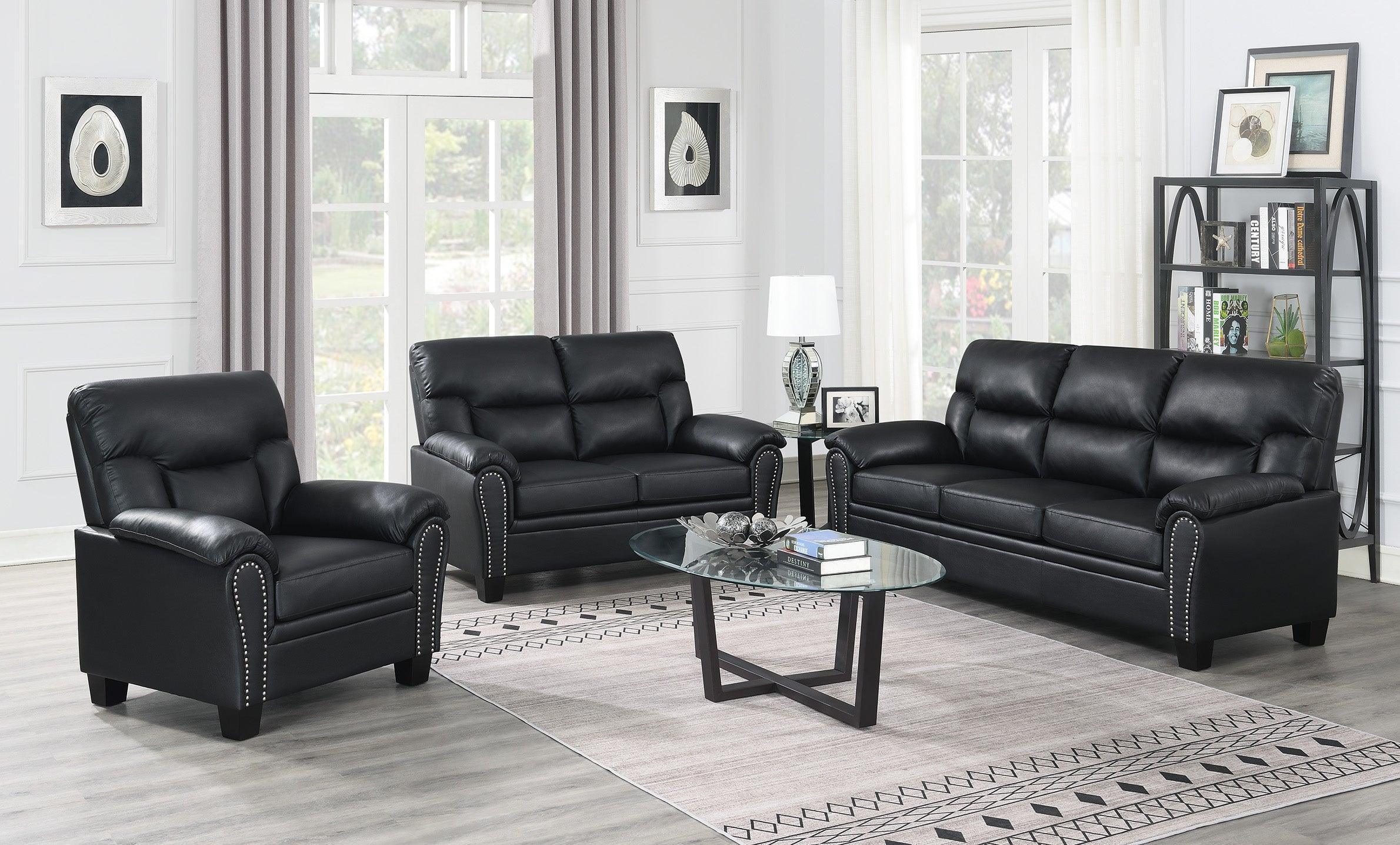 Modern black leather lounge suite with armchair, two sofas, and glass coffee table in bright living room