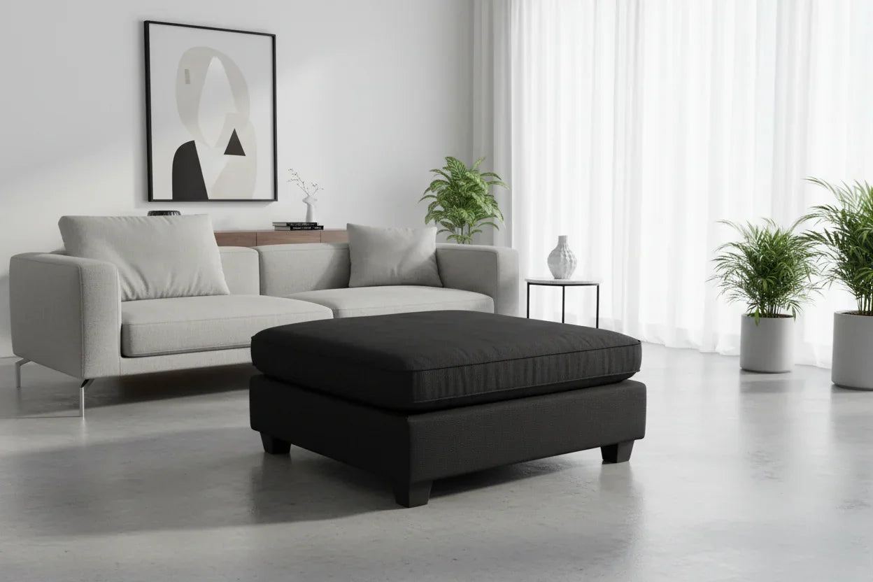 Modern living room with a gray sofa and black ottoman.