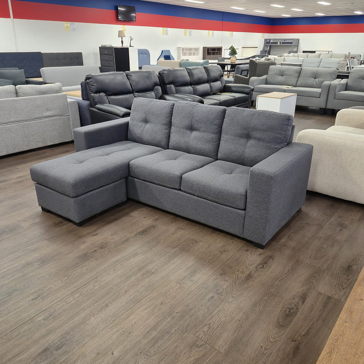 Sleek 3 Seater Chaise Lounge in dark grey fabric, angled front view showing the chaise and square arms, in The A2Z Furniture showroom
