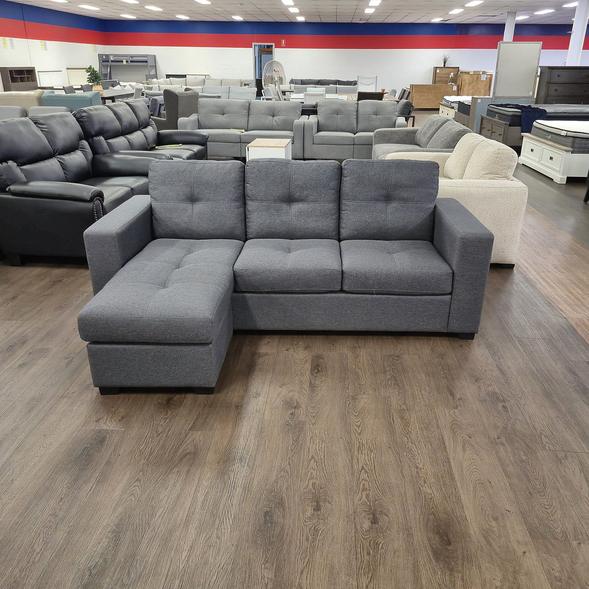 Sleek 3 Seater Chaise Lounge in dark grey fabric, front view showing the three tufted seat and back cushions, in The A2Z Furniture showroom