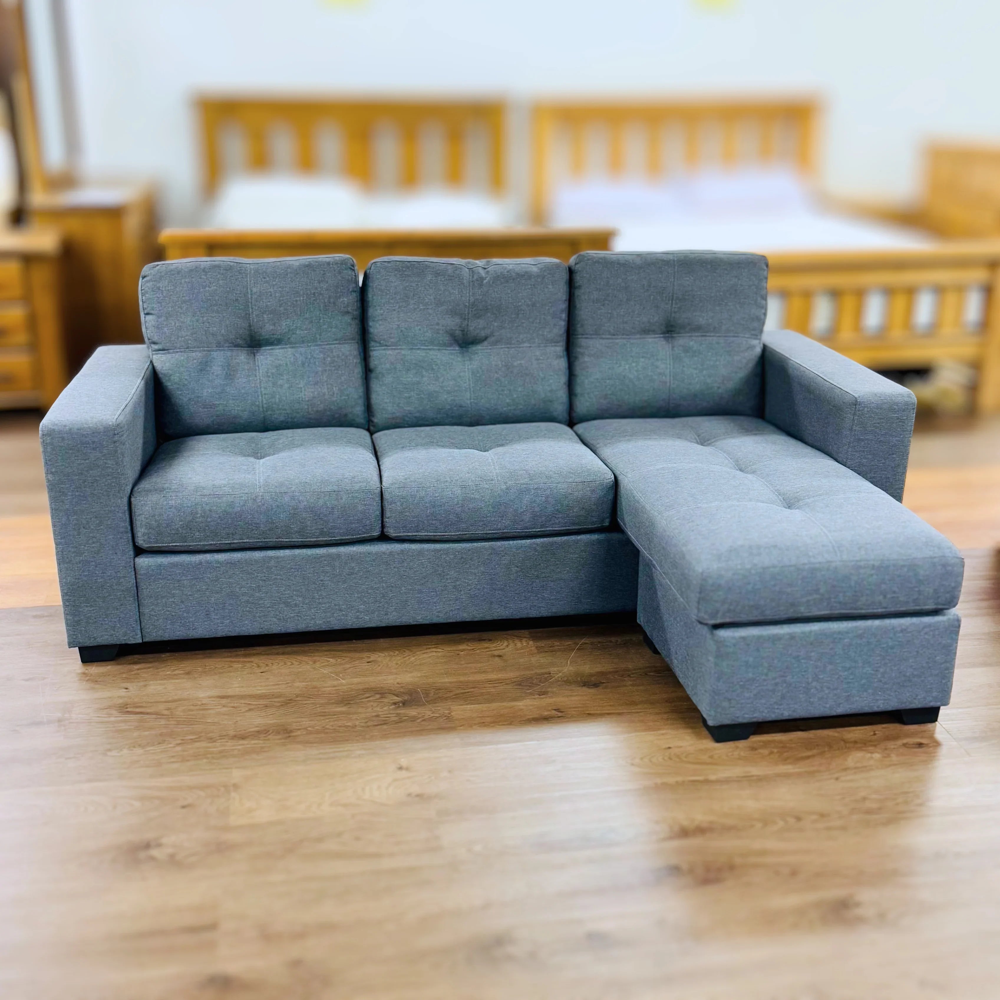 Modern grey fabric sectional sofa with chaise on timber floor in showroom setting