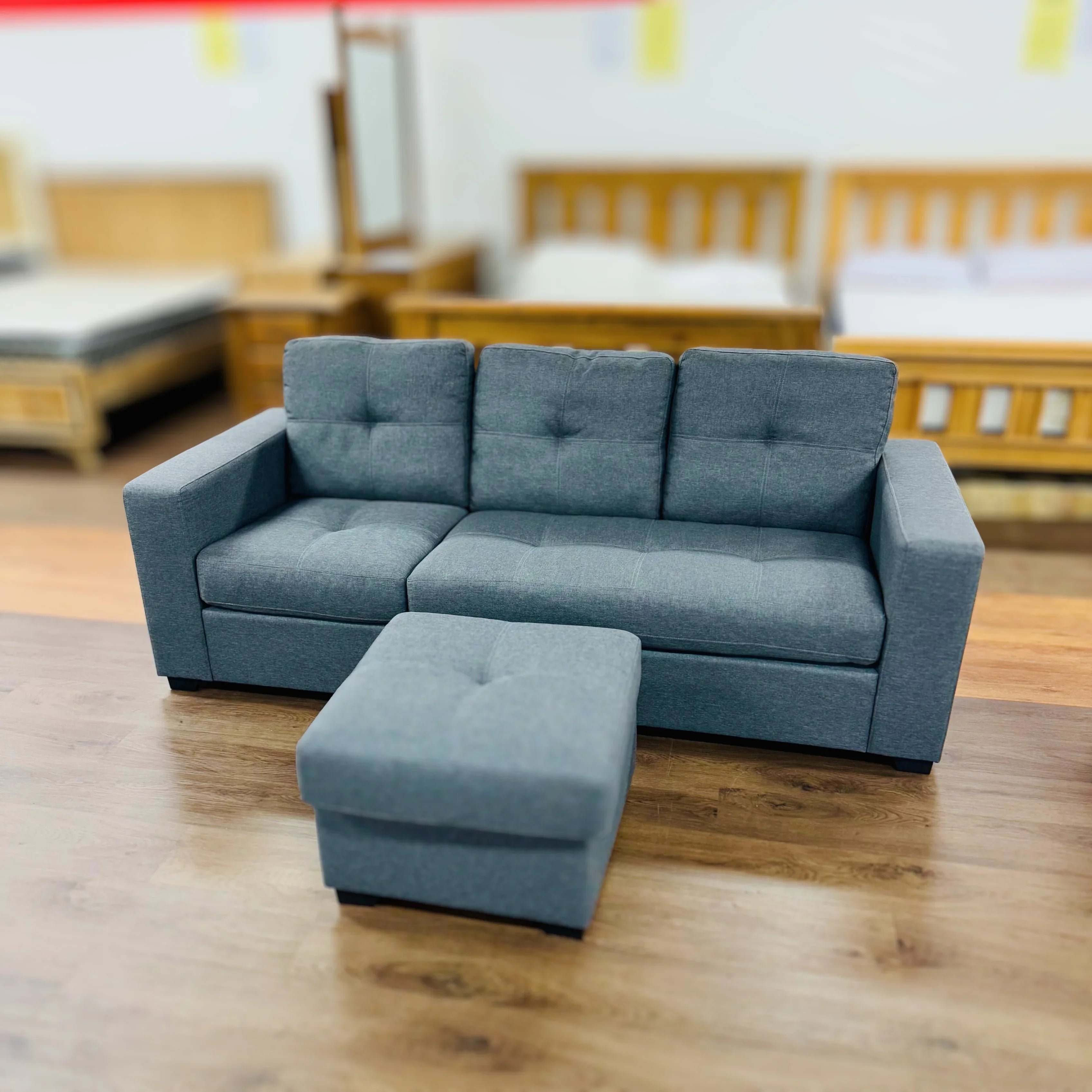 Modern grey fabric sofa with matching ottoman on wooden floor in furniture showroom
