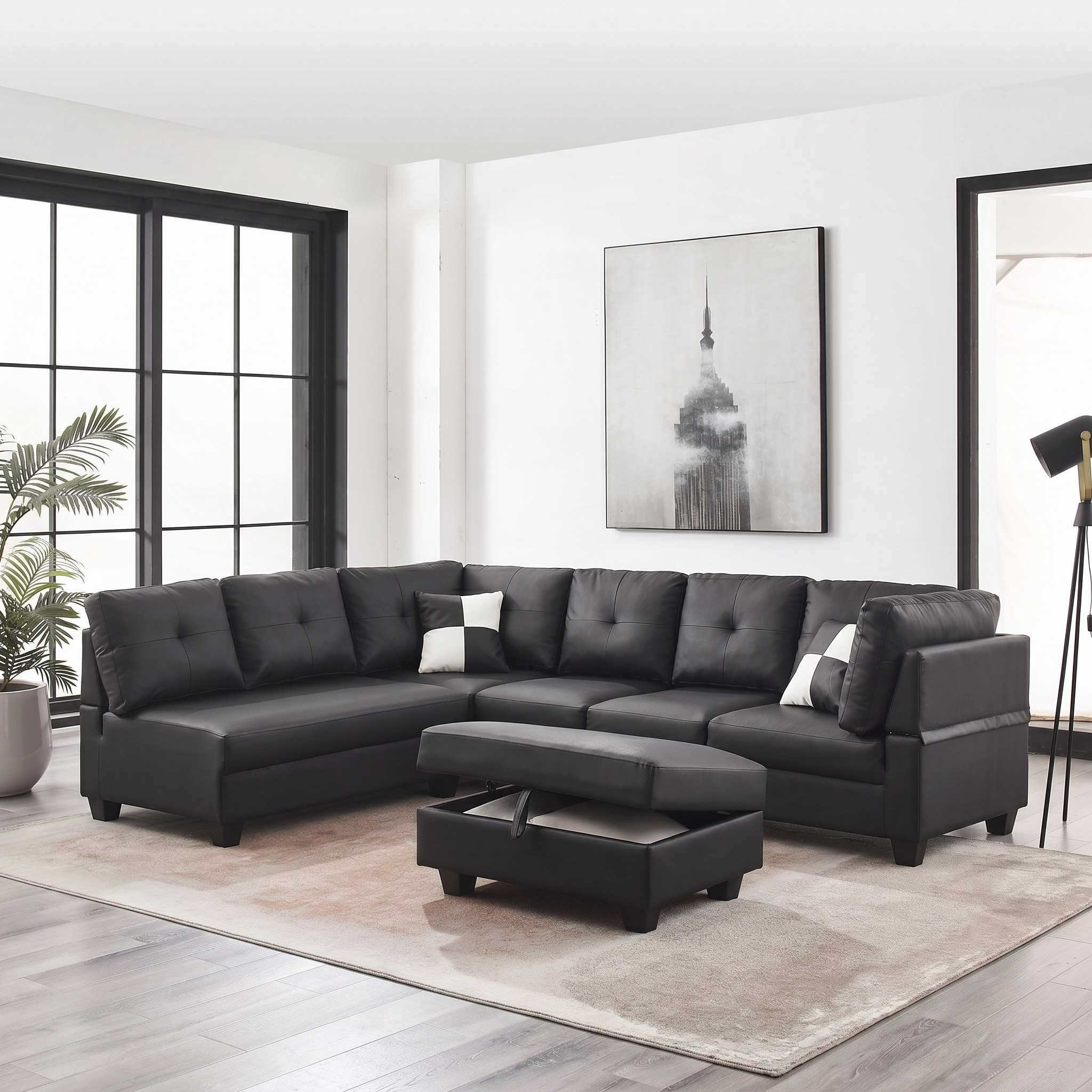 Black sectional sofa in a living room with a plant and artwork on the wall.