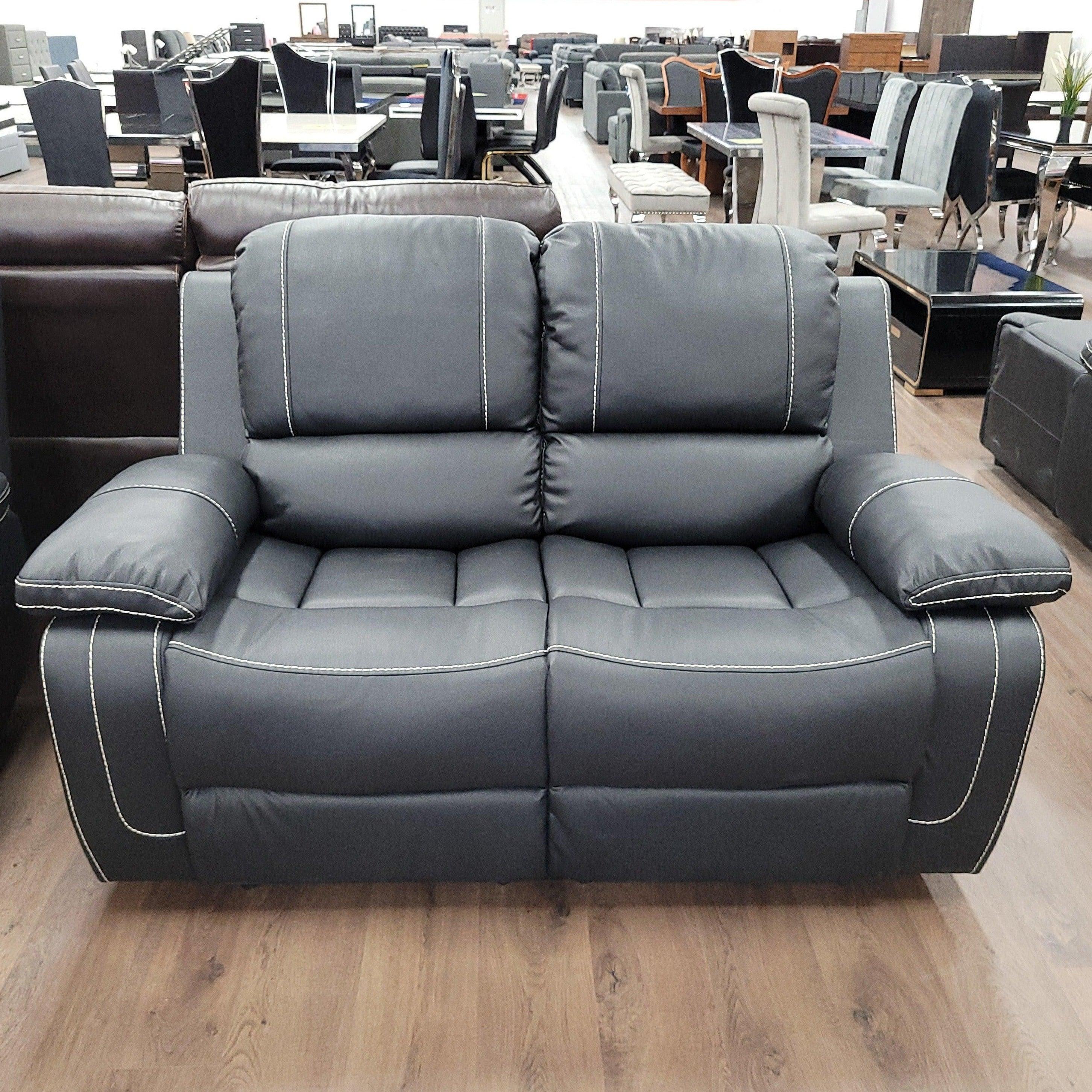 Dark grey 2-seater air leather recliner lounge with white stitching in a furniture showroom