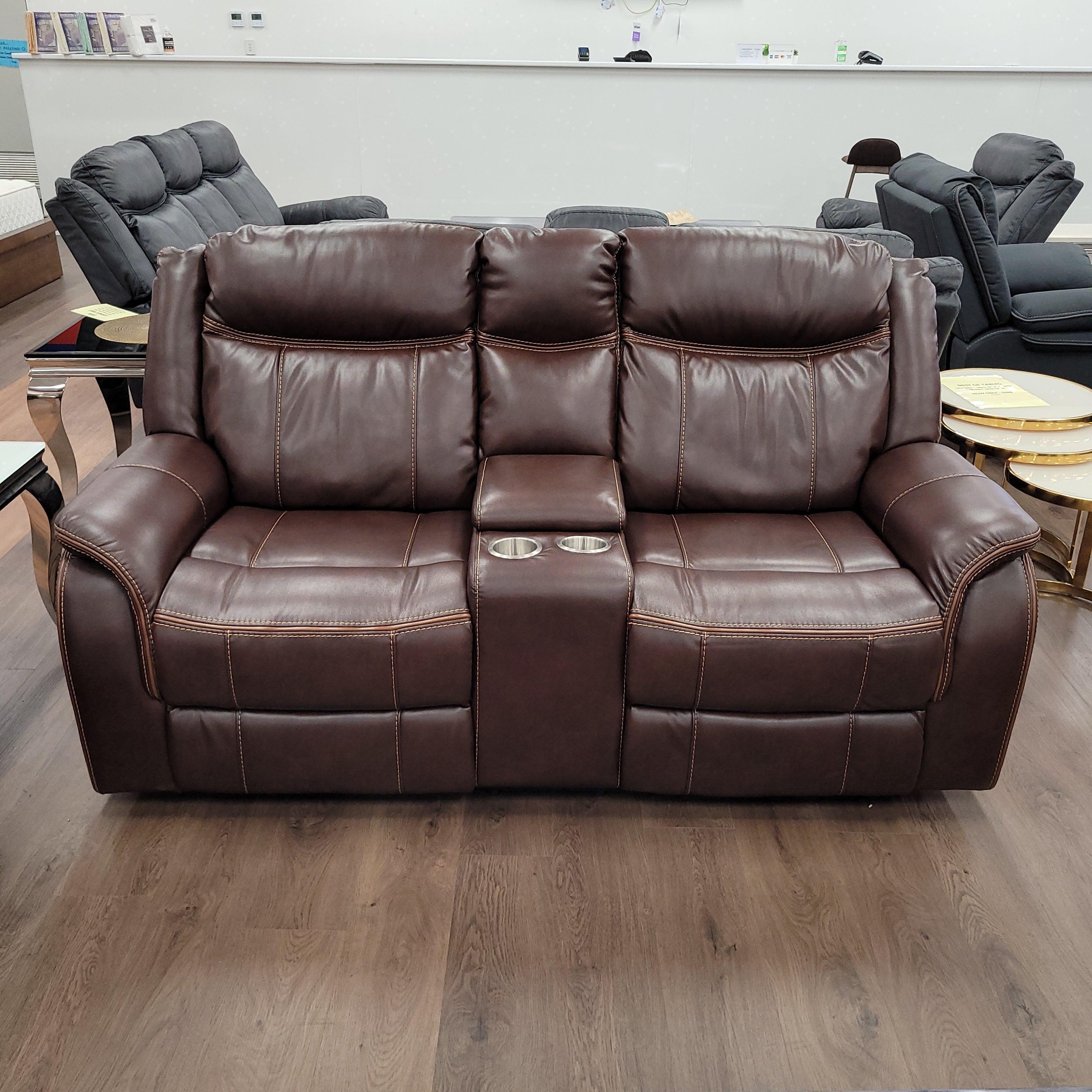 Brown leather 2-seater recliner lounge with cup holders in a showroom setting