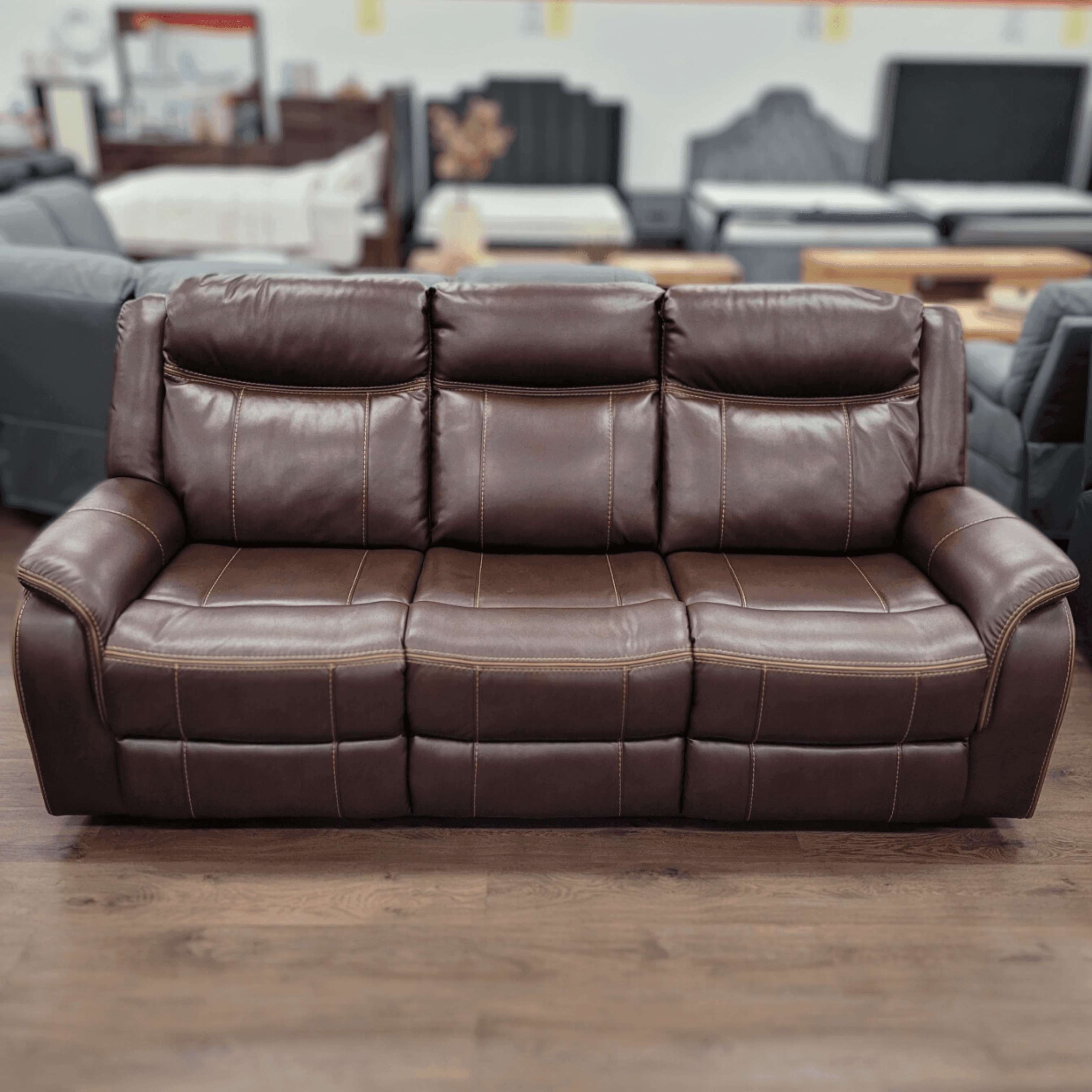 Brown leather 3 seater recliner sofa with stitching detail in showroom on wood floor