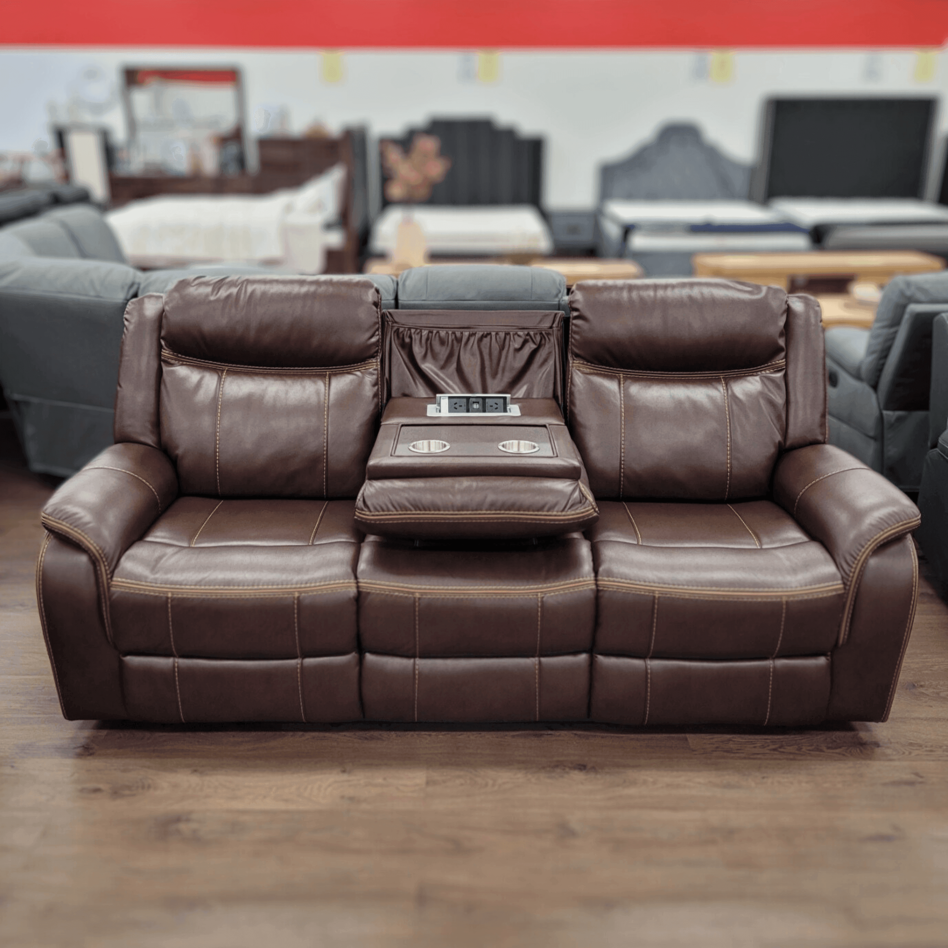 Brown leather 3 seater recliner sofa with center console and cup holders in showroom