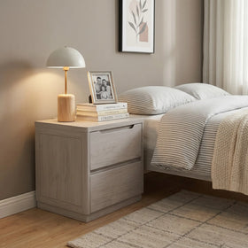 Cambridge bedside table in light grey timber finish with two drawers and recessed handles, styled beside a bed with a lamp and books - The A2Z Furniture