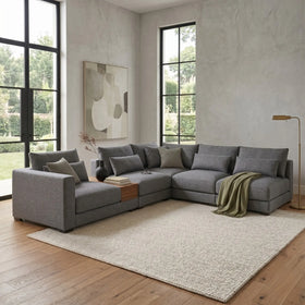 Gray sectional sofa in a modern living room with large windows and abstract art.