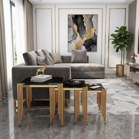Modern living room with gray sofa, gold and black nesting tables, and abstract art on the wall.