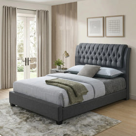Flair bed frame with grey fabric upholstery and a deep button-tufted winged headboard, styled in a neutral bedroom with curtains and wall art