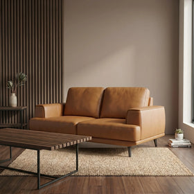 Picasso 2 Seater Leather Lounge in a warm caramel tone, set in a modern living room with a wooden slat coffee table, neutral rug, and minimalist decor for a cozy stylish look.