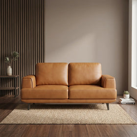 Picasso 2 Seater Leather Lounge in tan brown with sleek armrests and slim legs, placed on a textured rug in a modern living room with neutral tones and minimalist decor.
