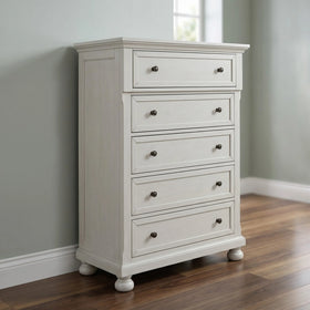 White tallboy with multiple drawers on a wooden floor against a gray wall
