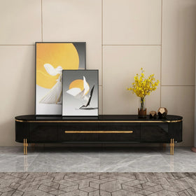 Modern black and gold TV stand with decorative items against a beige wall.