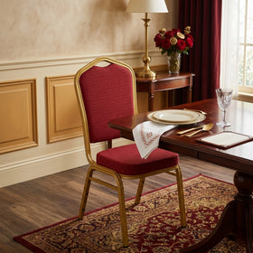 Glamour dining chair with red patterned fabric seat and back on a gold metal frame, shown at a formal table setting in an elegant dining room
