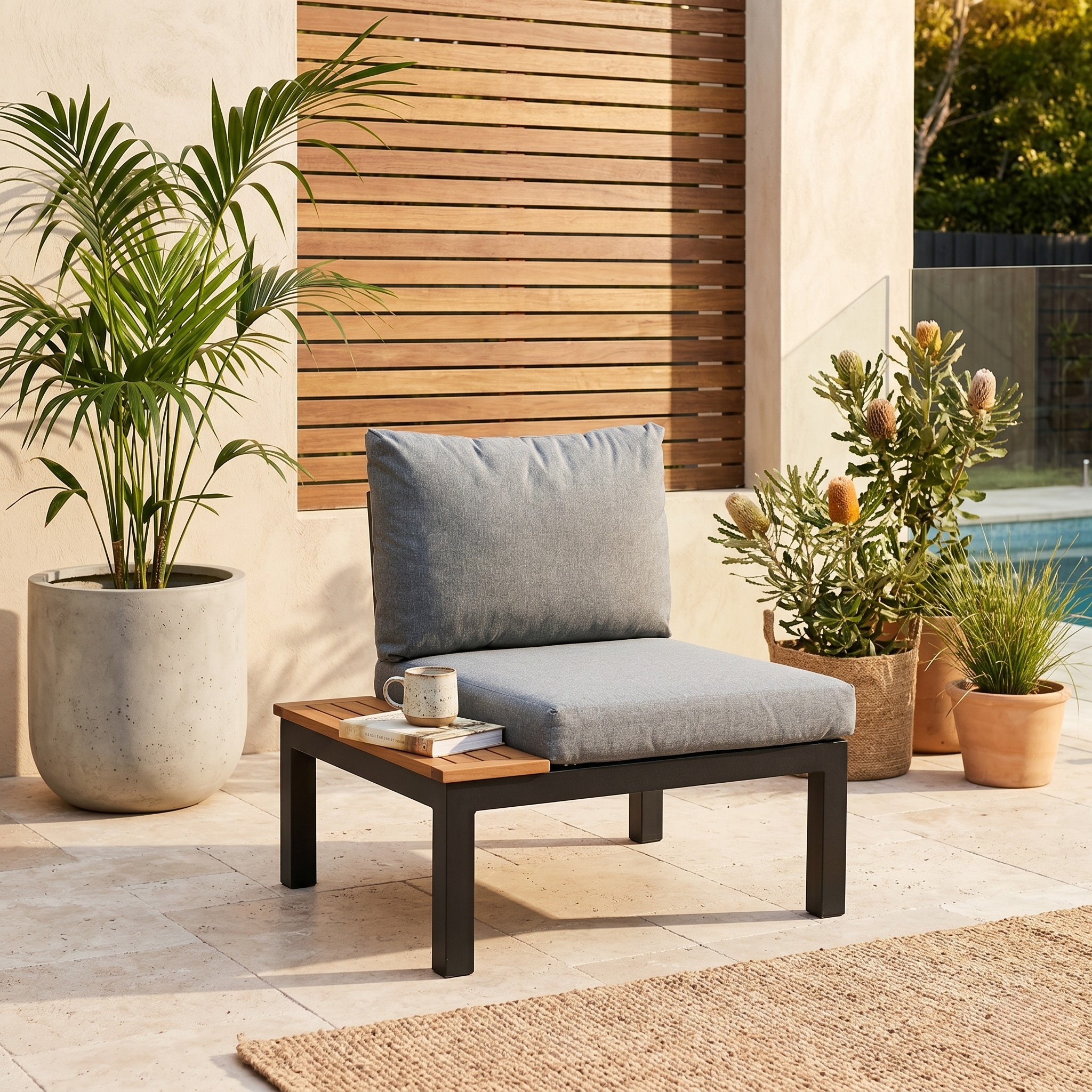 Outdoor patio chair with gray cushions and a small table, surrounded by potted plants.