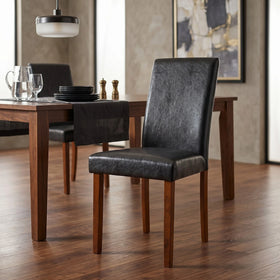 Dixon Chair in black faux leather with warm timber legs, set beside a walnut dining table in a styled dining room - The A2Z Furniture