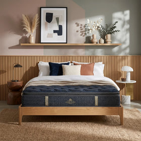 Bedroom with a wooden bed frame, blue mattress, and decorative pillows.