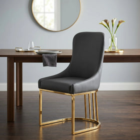 Drome dining chair in dark grey leather-look upholstery with a curved high back and polished gold metal base, beside a timber dining table - The A2Z Furniture