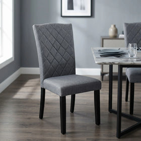 Daybreak Chair upholstered in grey fabric with a diamond-stitched back and black tapered legs, beside a marble-top dining table