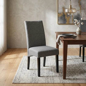 Dexter Chair in black faux leather with mid-brown timber legs, styled beside a walnut dining table in a warm neutral room - The A2Z Furniture