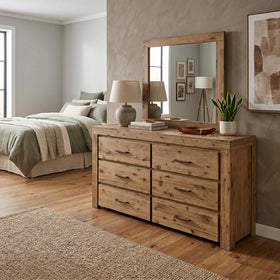 Wooden dresser in a bedroom with a mirror above it, books, and decorative items.