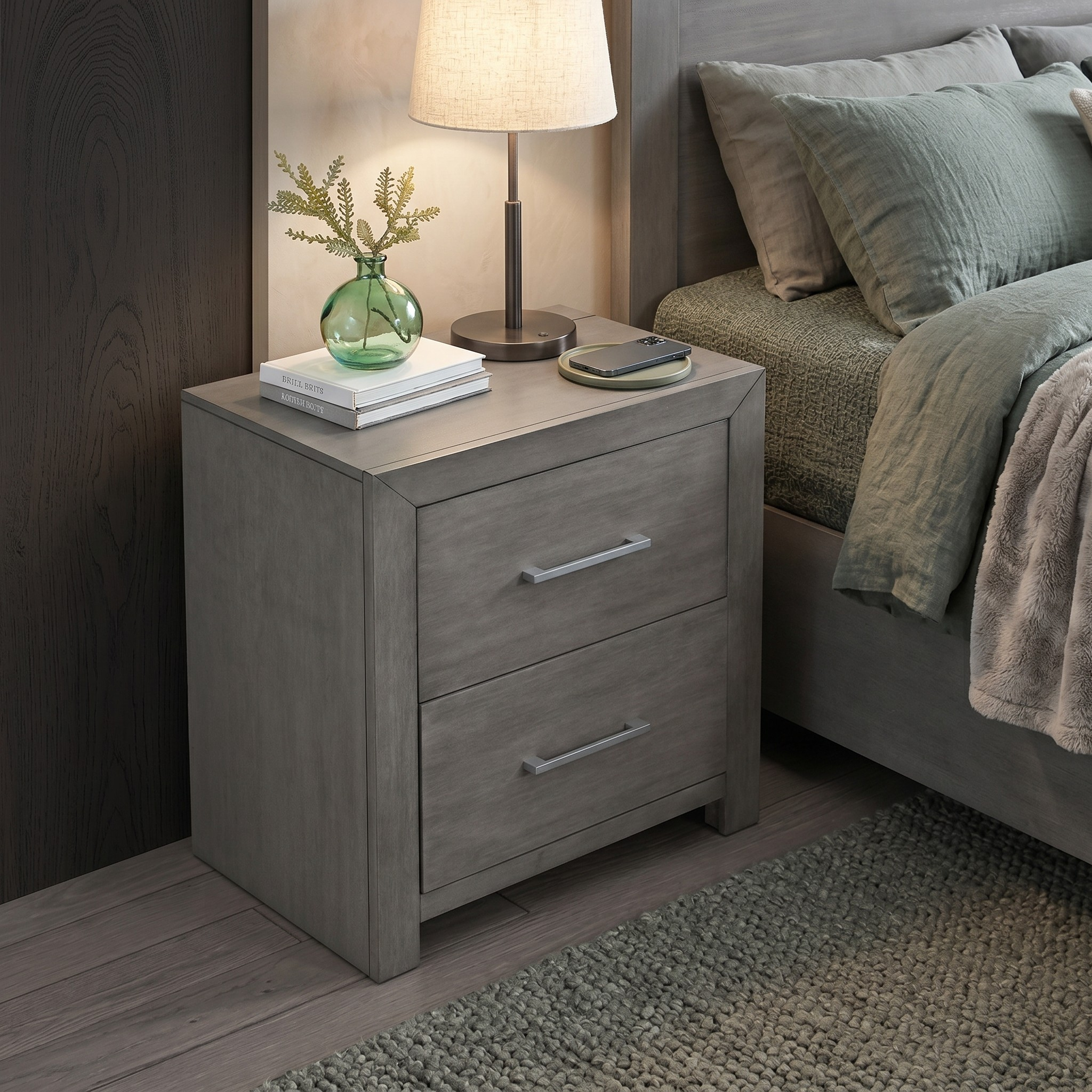 Gray nightstand with two drawers next to a bed with green bedding.