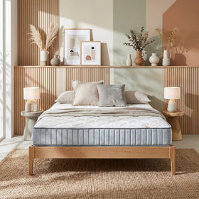 Sleep Rest King Single Mattress on a wooden bed frame in a bright, modern bedroom with neutral-toned pillows, textured rug, and decorative vases on a wooden shelf.