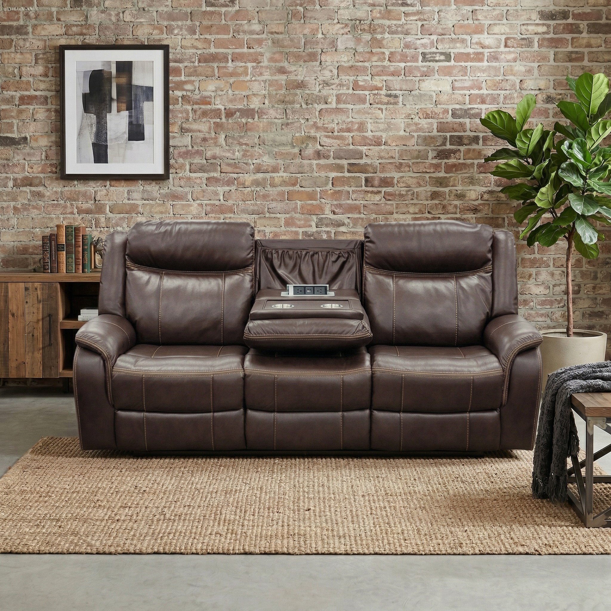 Brown leather sofa in a room with a brick wall, books, and a plant.