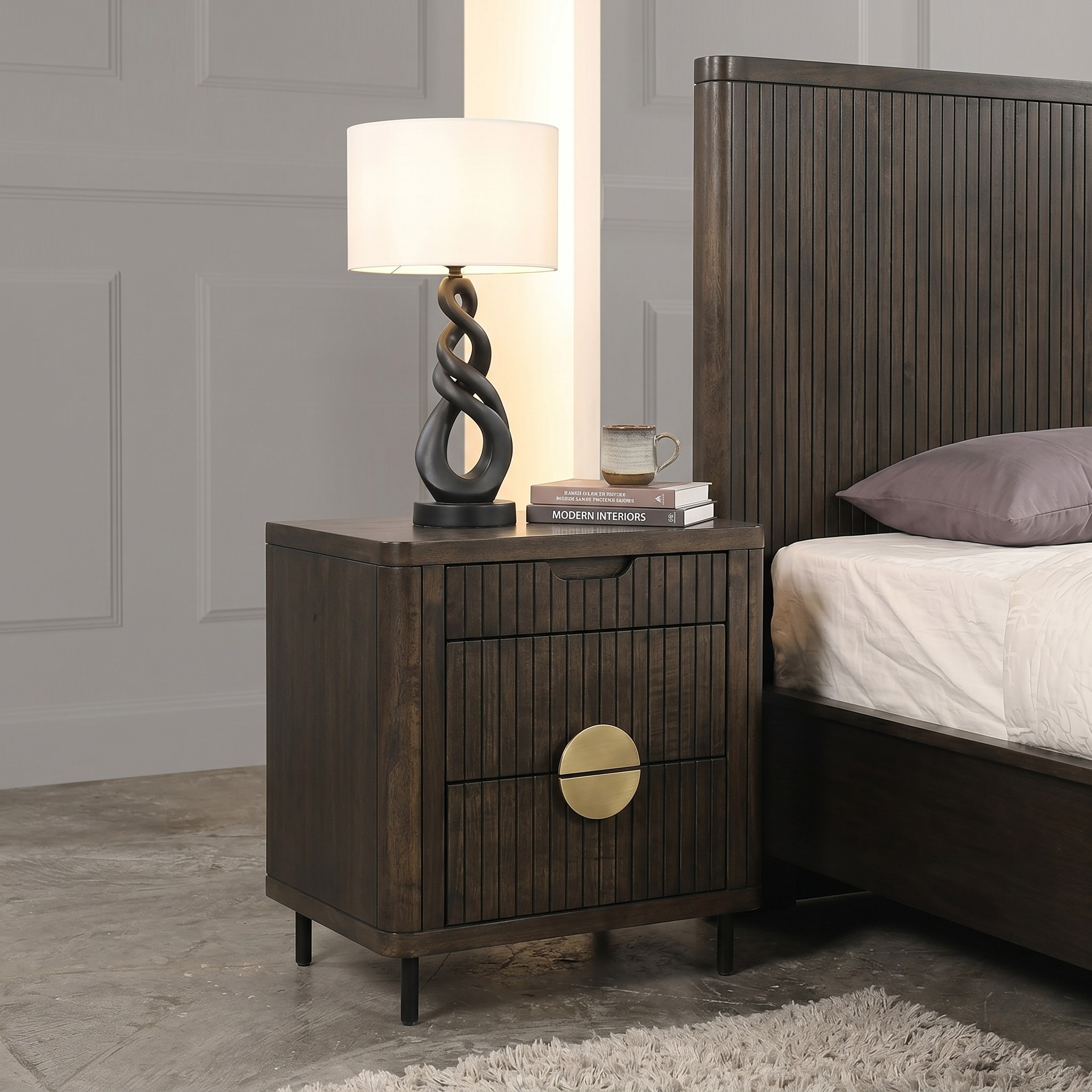 Wooden nightstand with lamp and books next to a bed in a bedroom setting.