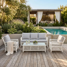 Outdoor patio set with gray cushions and white wicker chairs by a pool