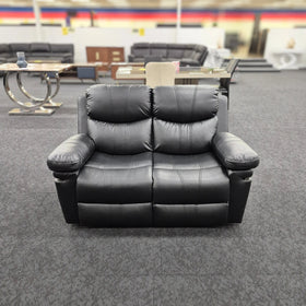 Black 2 seater air leather recliner lounge with padded armrests in a showroom
