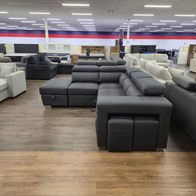 Alice Sofa Bed in black fabric, rear view showing the two matching hideaway stools tucked under the ottoman arm, in The A2Z Furniture showroom