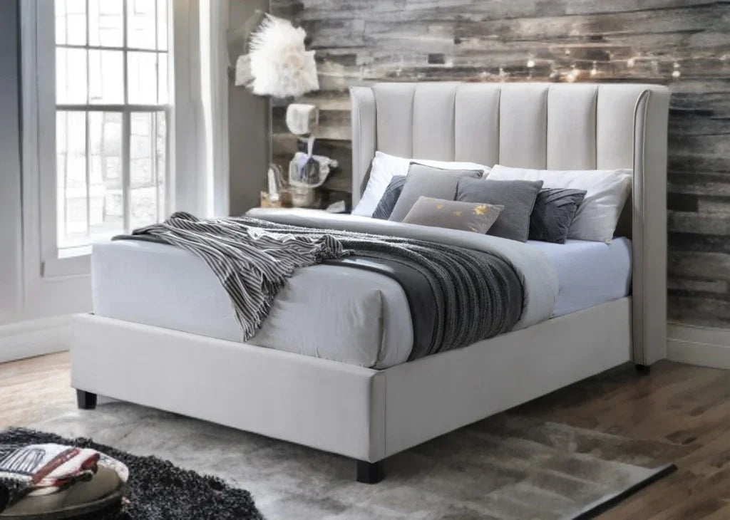Modern oatmeal upholstered bed with tall headboard, layered pillows and cozy bedding in a stylish bedroom