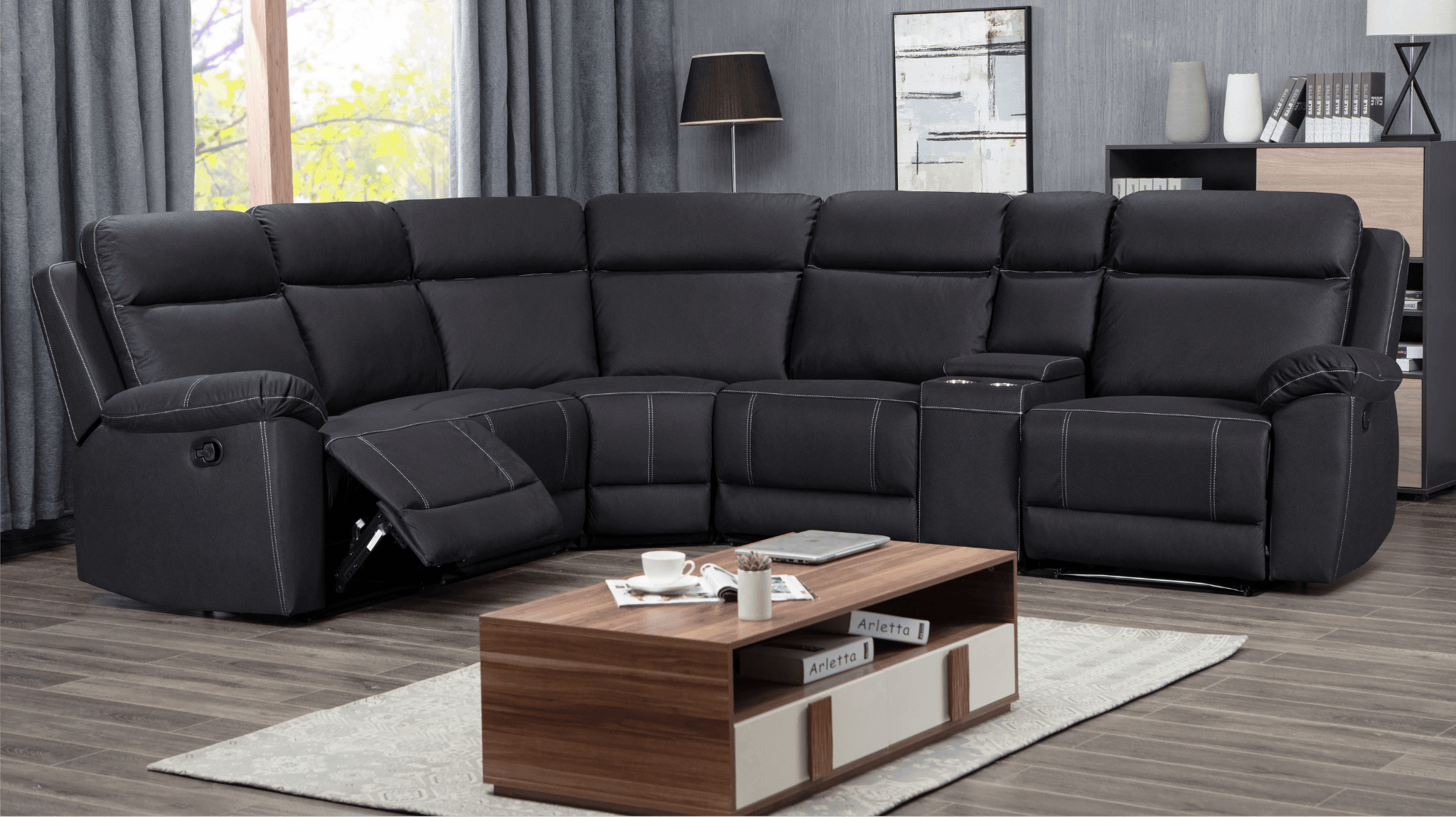 Modern black reclining sectional sofa in a living room with coffee table and decor