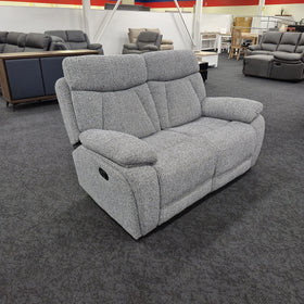 Baker 2 seater recliner lounge in speckled grey fabric viewed at an angle in The A2Z Furniture showroom, with the black manual recline pull handle visible on the outside arm