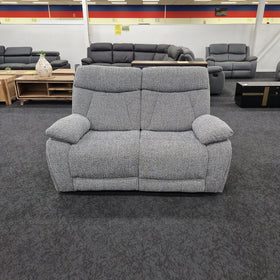 Baker 2 seater recliner lounge in speckled grey fabric seen front on in The A2Z Furniture showroom, showing two seat cushions and padded scatter armrests