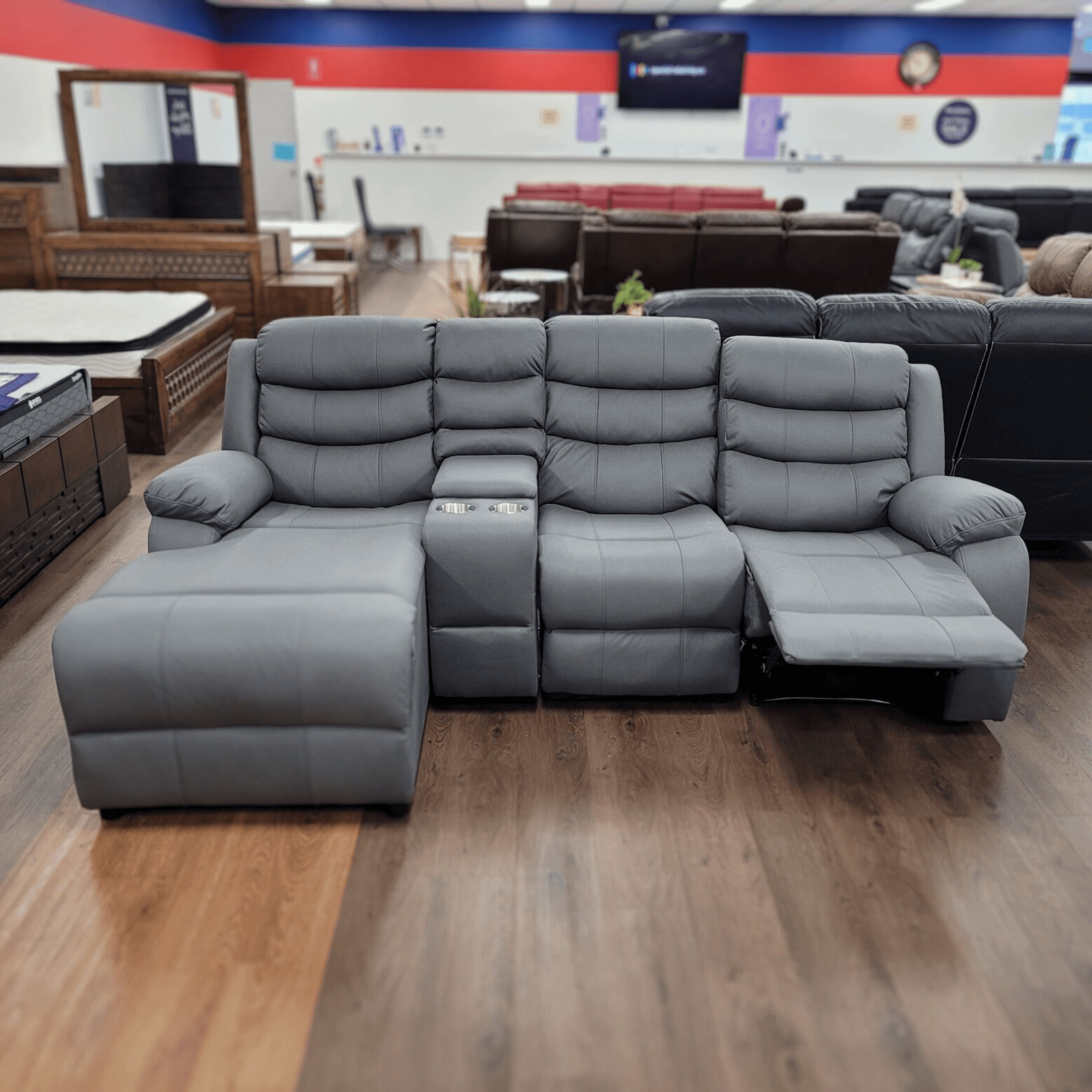 Gray L-shaped recliner sectional sofa with chaise lounge in a furniture showroom