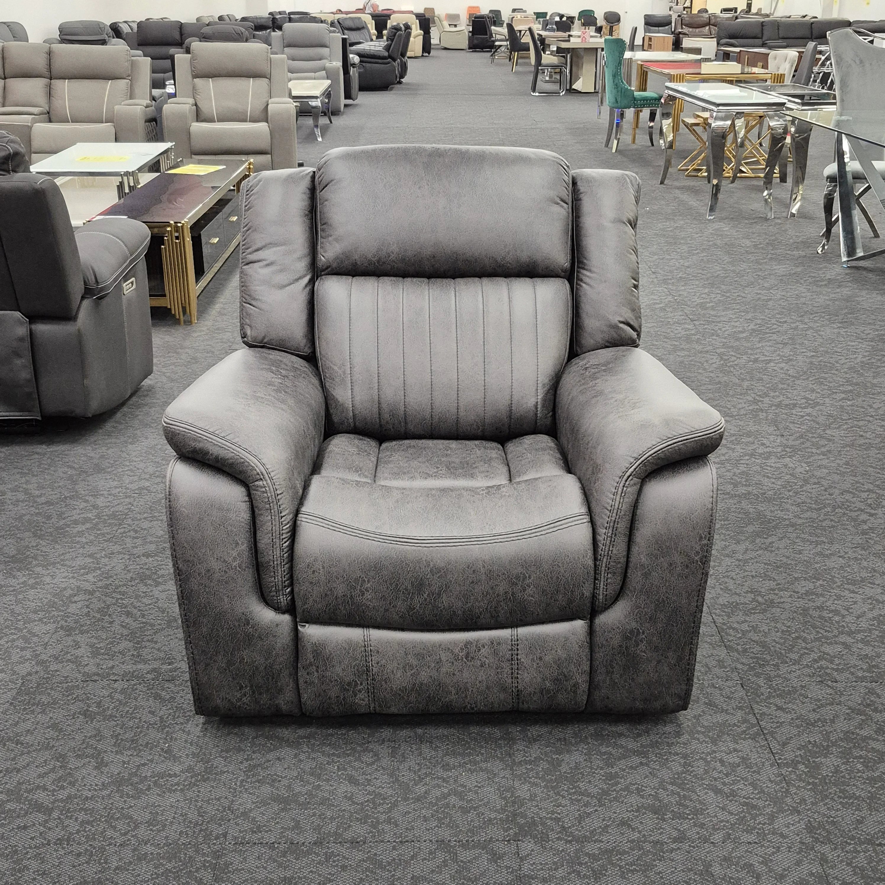 Gray upholstered recliner armchair on display in a furniture showroom with sofas and tables