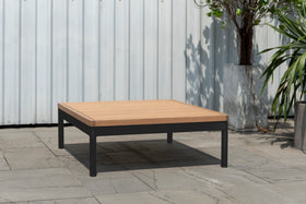 Outdoor square coffee table with light wood top and black metal legs on a patio