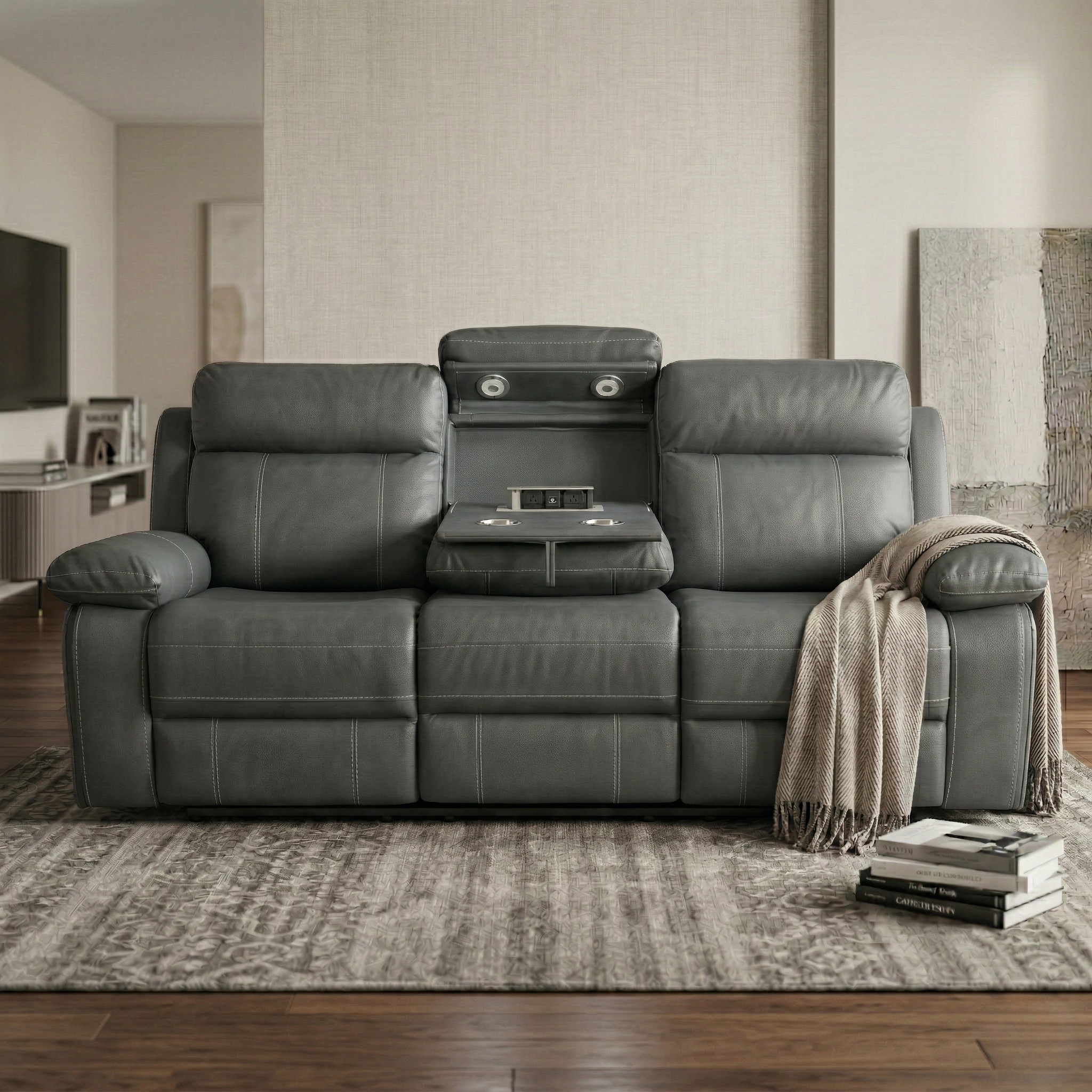 Charcoal reclining sofa in a living room setting with a blanket and books on it.