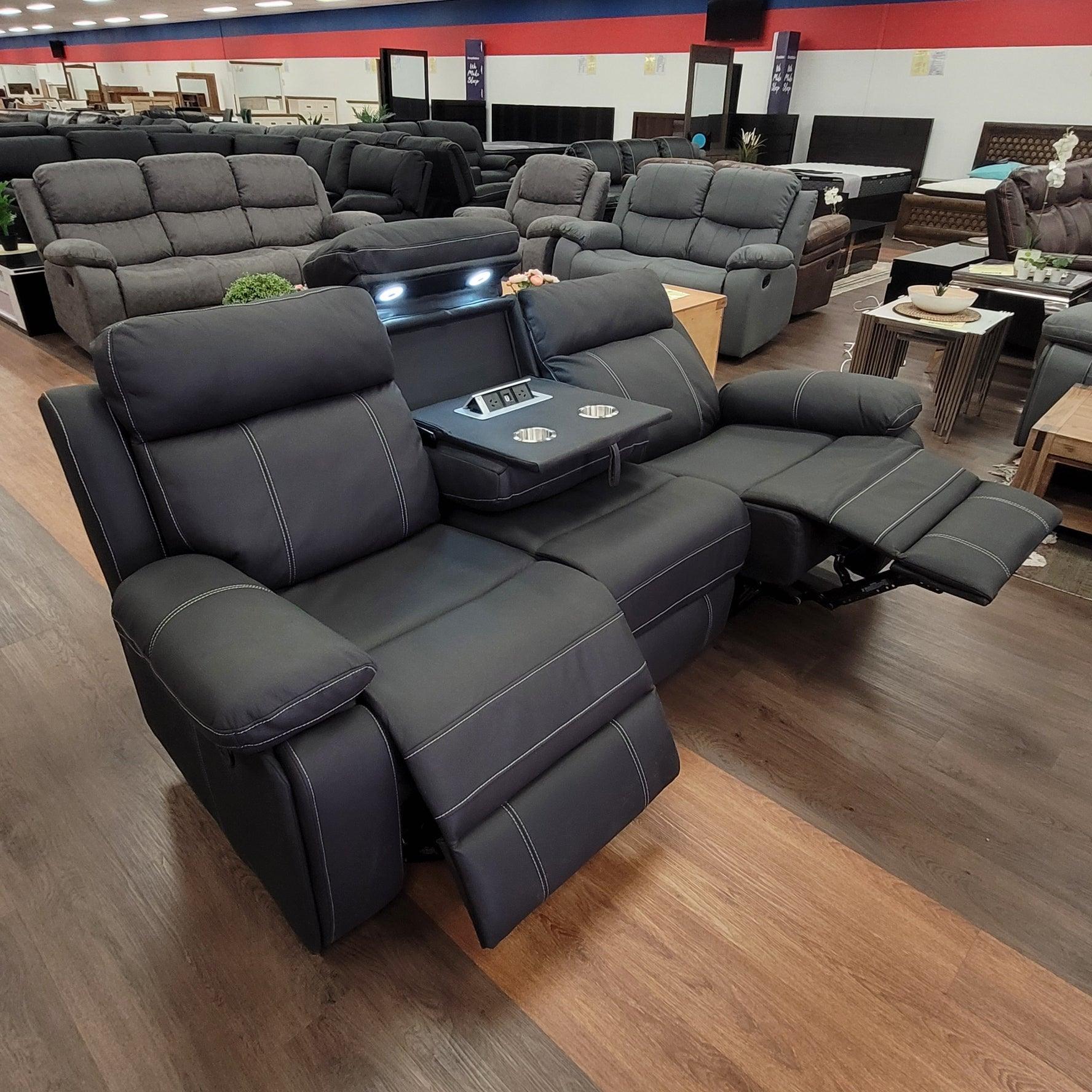 Black three-seater recliner sofa with cup holders and built-in lights in a furniture showroom
