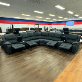 Modern black sectional recliner sofa with LED lights and cup holders in showroom