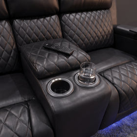 Close-up of the Blair theatre recliner centre console with twin cup holders and padded storage lid in black diamond-quilted air leather