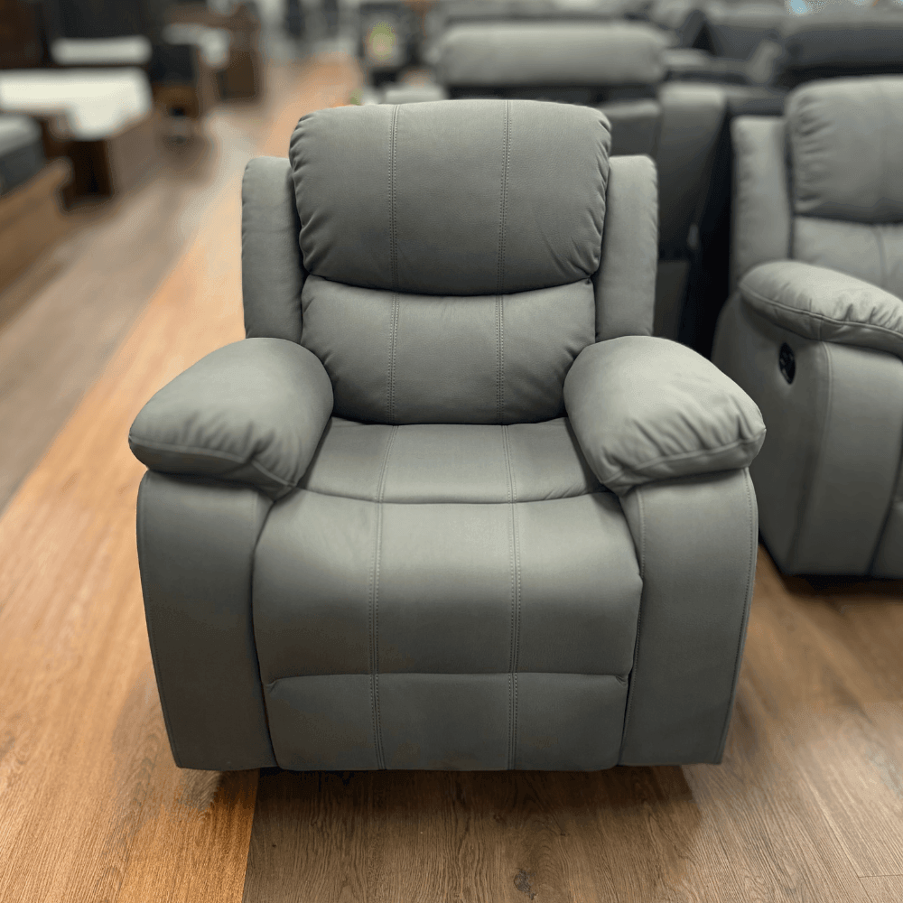 Charcoal grey fabric recliner armchair with plush cushions on a wooden showroom floor