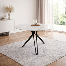 Bondi round dining table — white marble-look top on a black three-leg flat-strap base, in a bright dining room